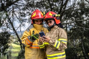 Firefighters using mobile phone outdoors